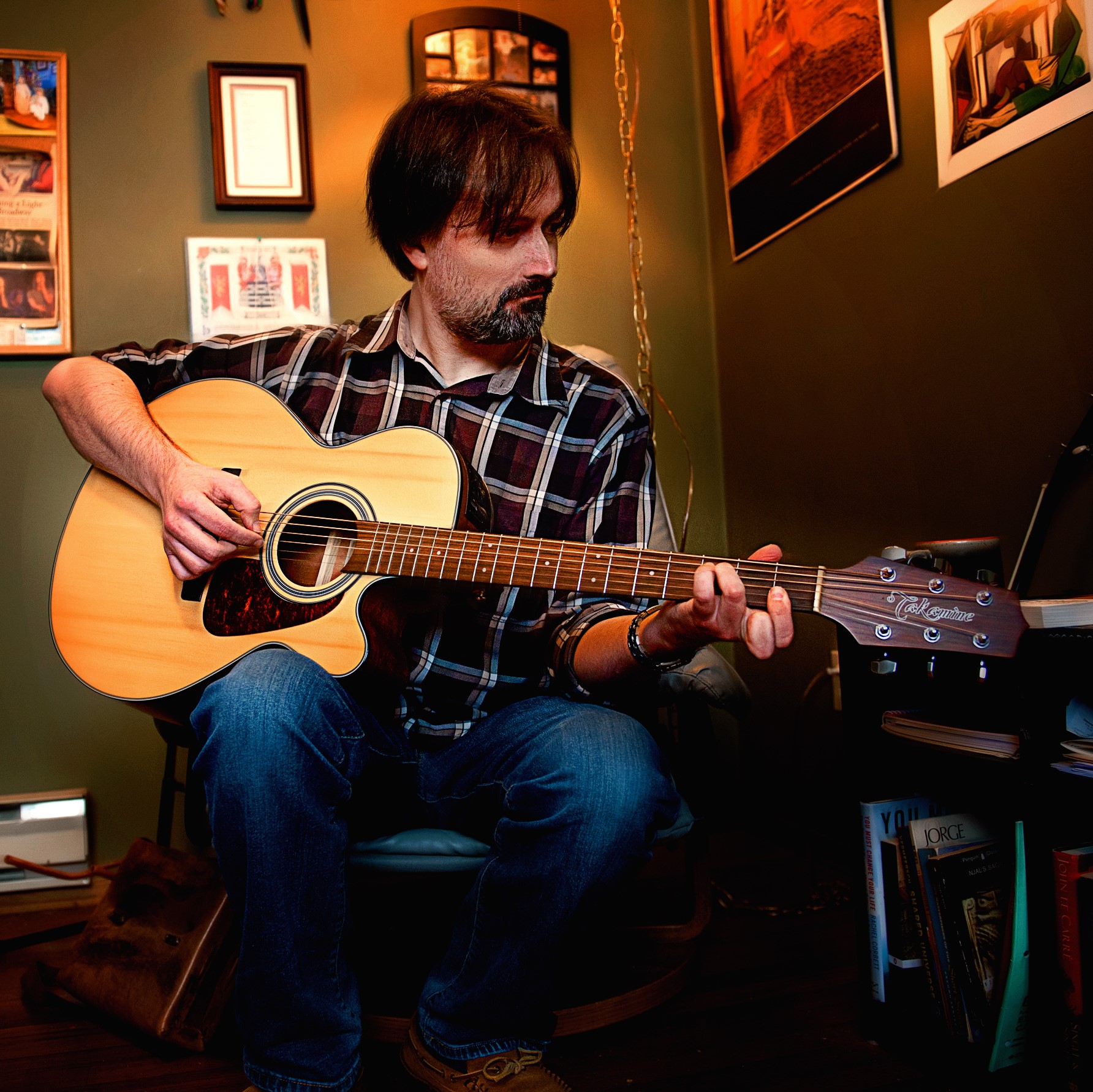 Kevin Imrie, SK Arts 75th anniversary nominee -  Man with medium length brown hair and plaid shirt playing guitar.