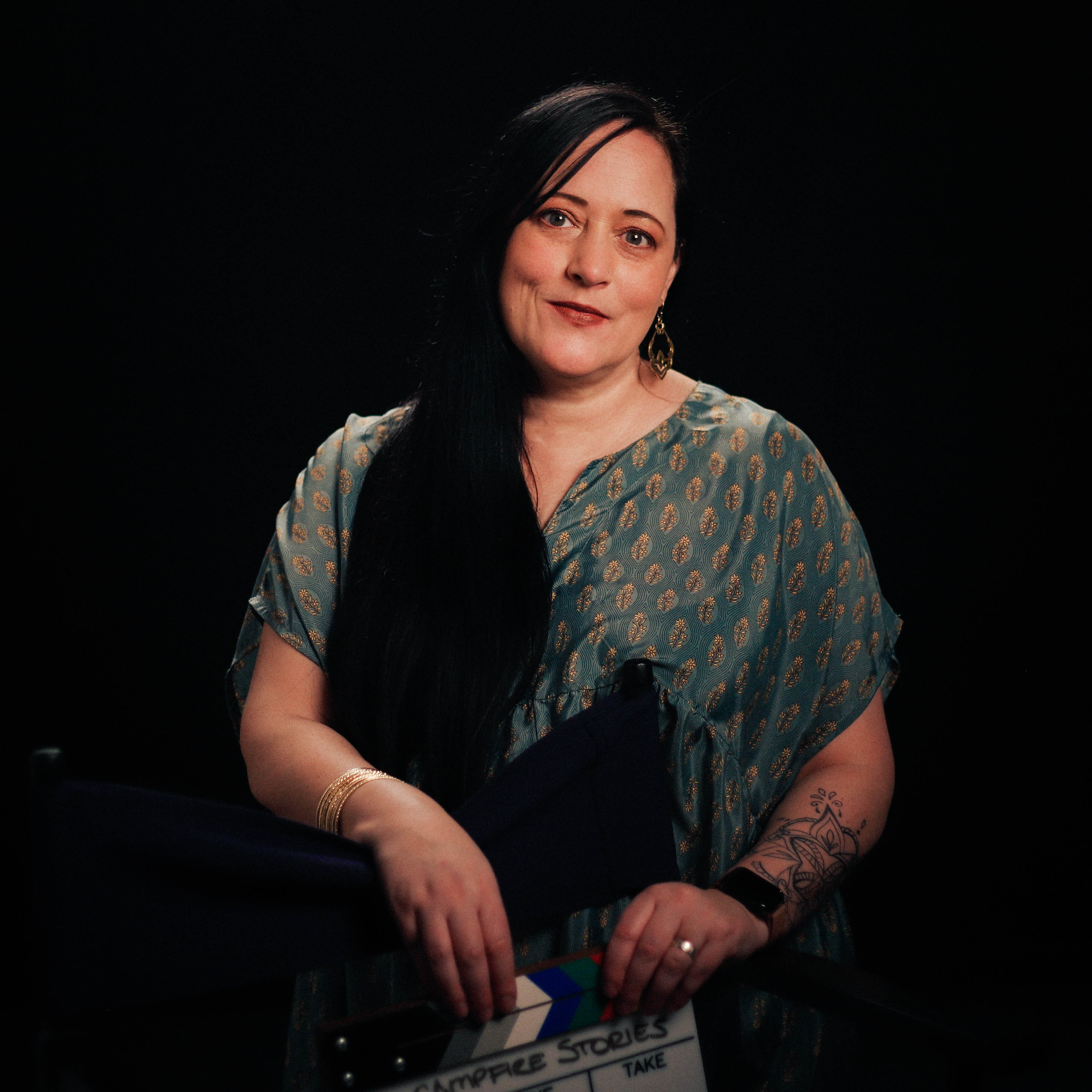 Allia Janzen - Portrait of indigenous woman with long black hair holding a film clapboard.