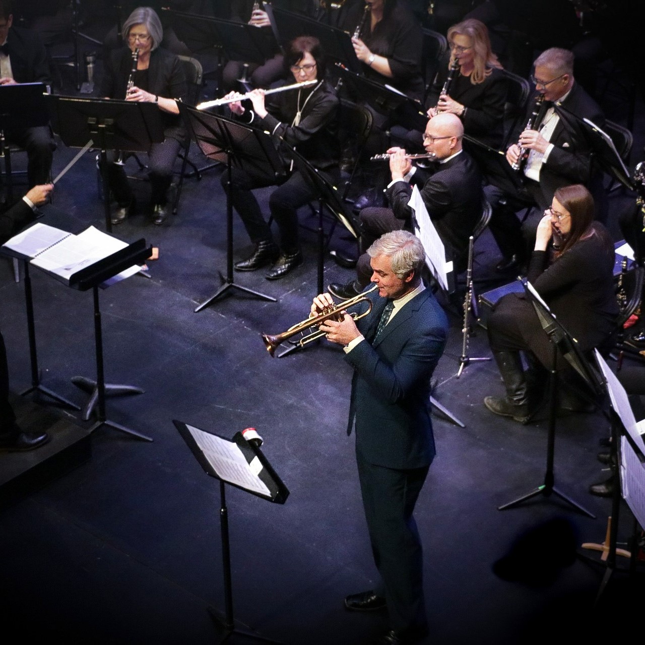 Dean McNeill - Man on a stage wearing a suit and blowing an instrument.