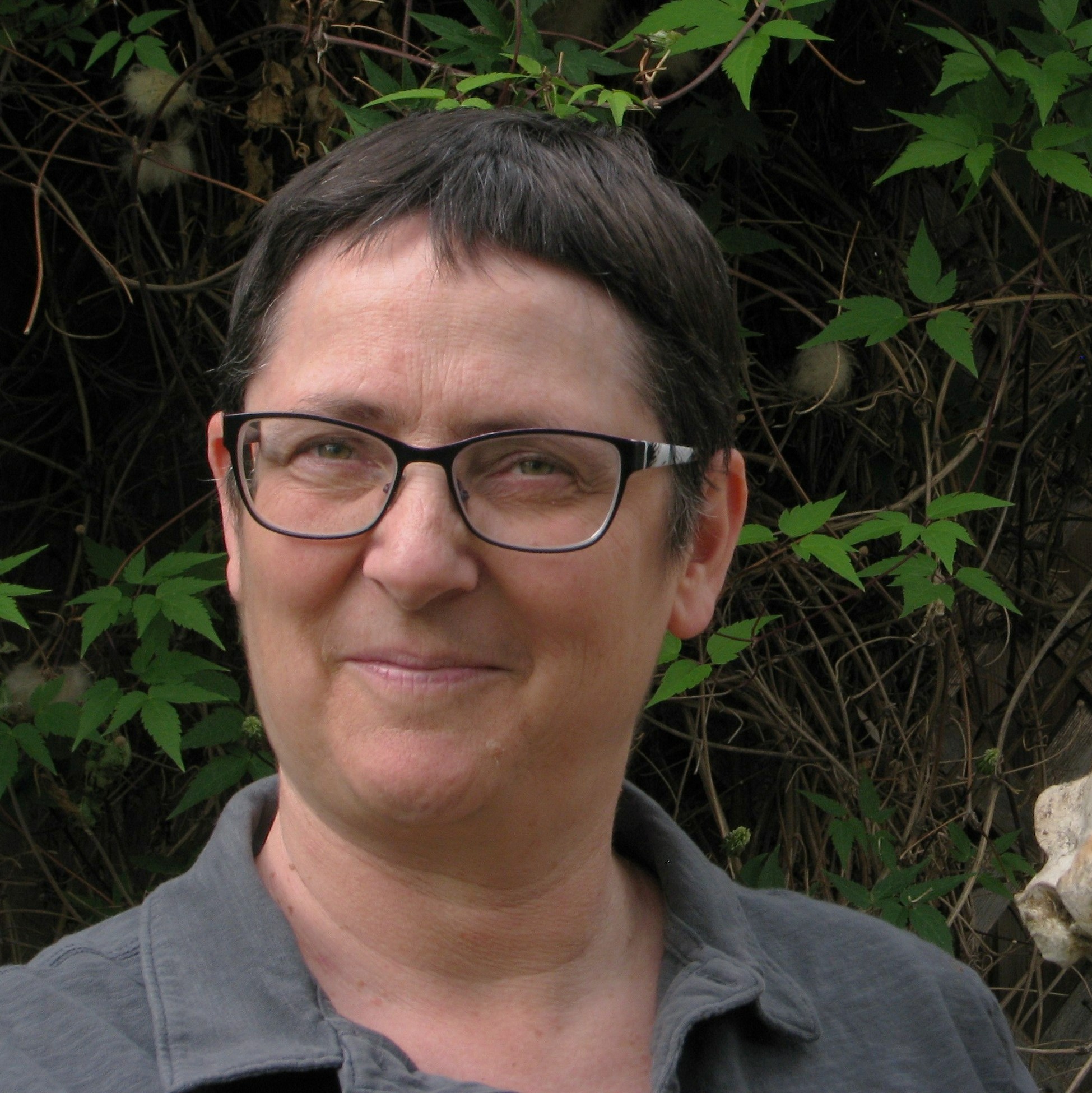 Elizabeth Phillips - Portrait of smiling woman with low cut brown hair wearing glasses