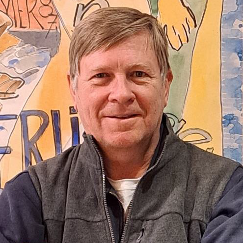 Wayne Baerwaldt - Portrait photo on blond man wearing a gray jacket smiling.