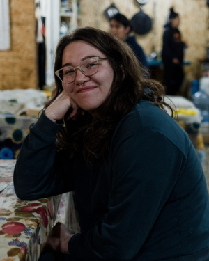 Portrait of woman with dark brown hair and thin rimmed glasses smiling - Holly Aubichon credit to Tenille Campbell