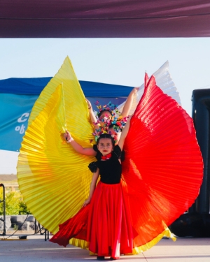 Latino Festival Children on stage performing in large fanned out orange and red skirts