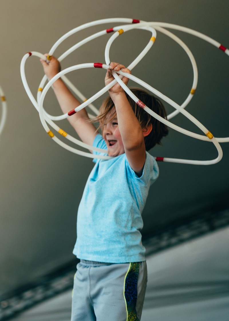 A child holds several hoops above his head.