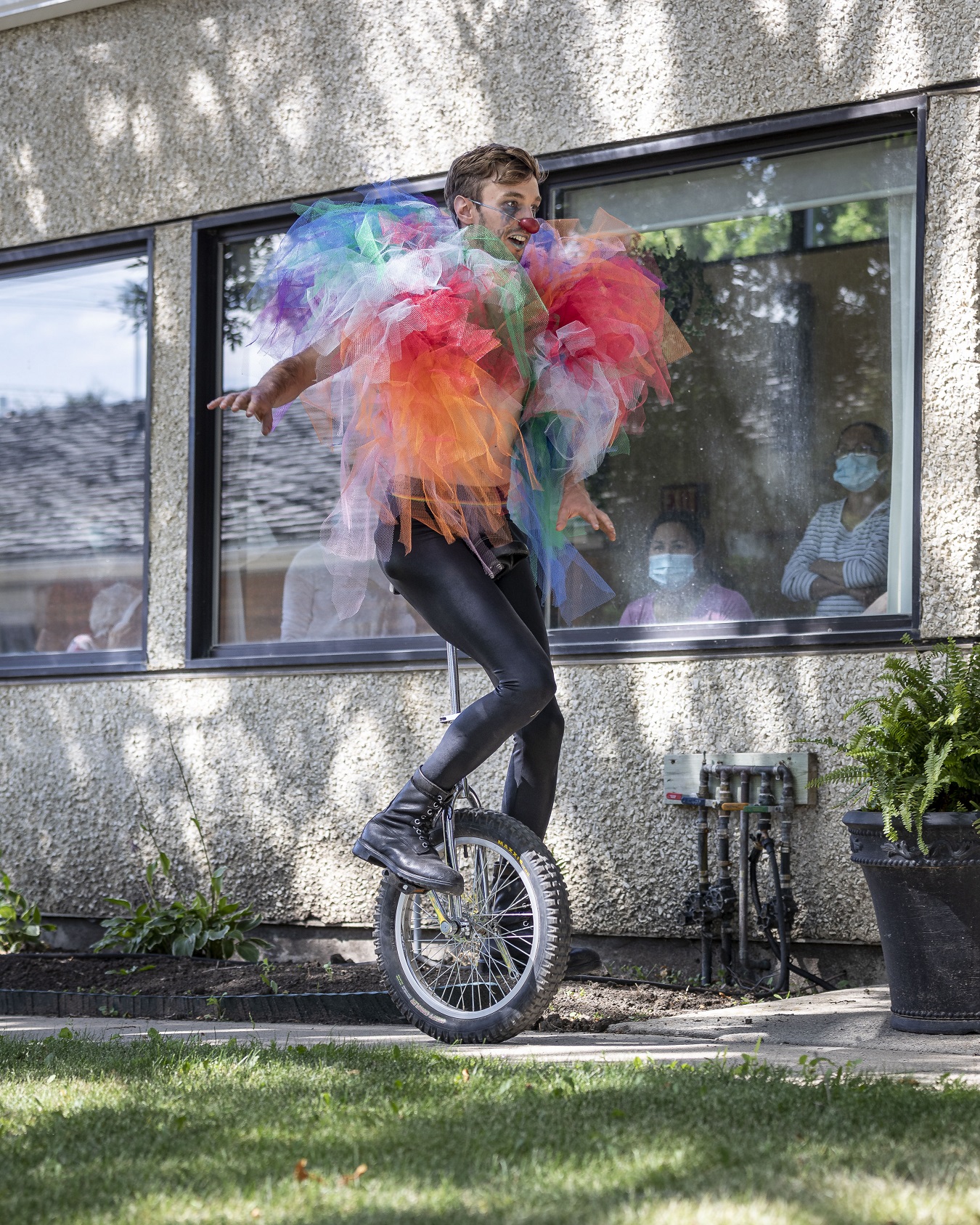 A man dressed as a clown rides a unicycle.