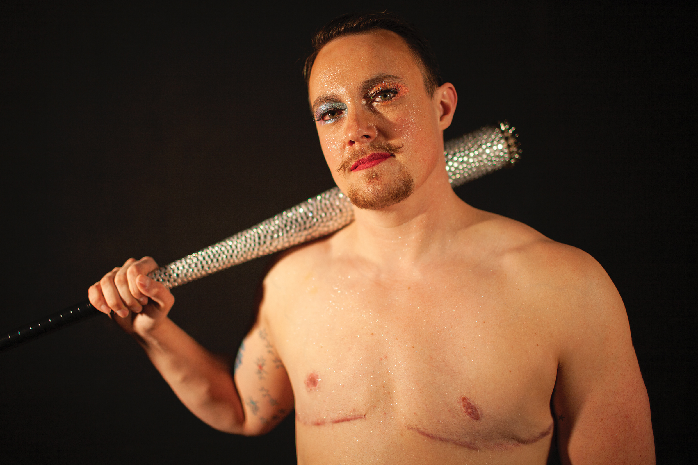 A trans man holding a sparkly bat.