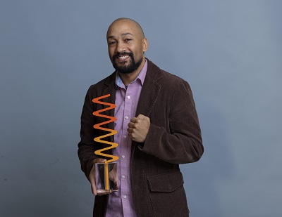 Khodi Dill holding his Saskatchewan Arts Award sculpture