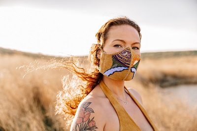 Vanessa Hyggen standing in a field wearing a beaded face mask