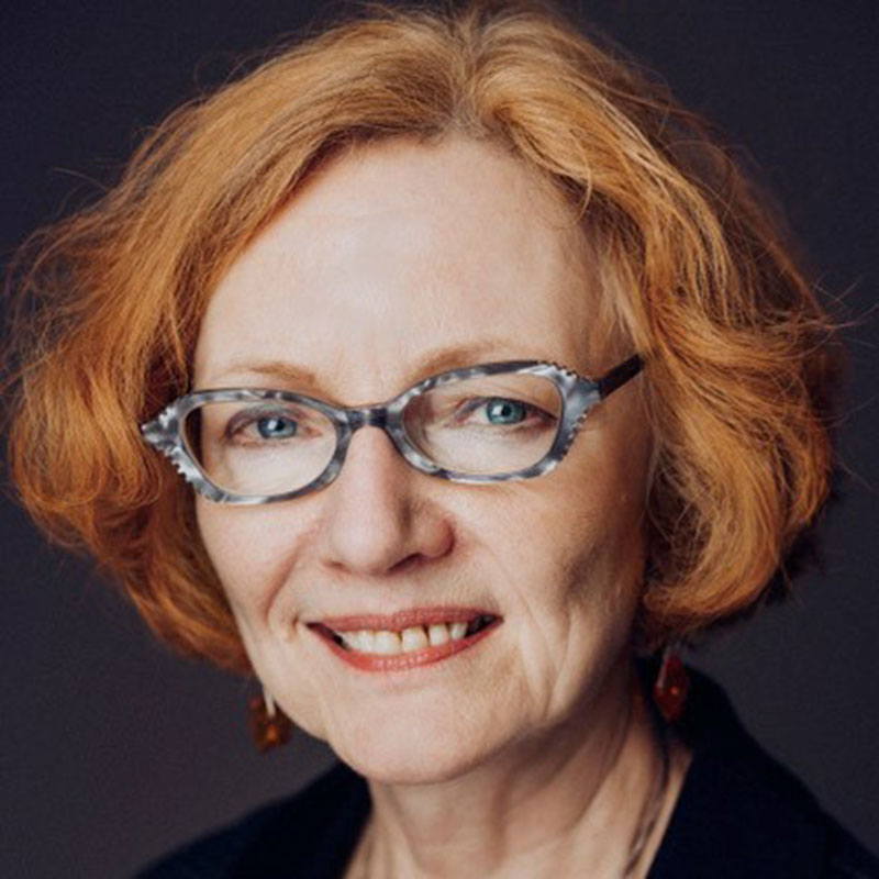 Mari-Lou Rowley - Older woman with short ginger red hair and glasses smiling