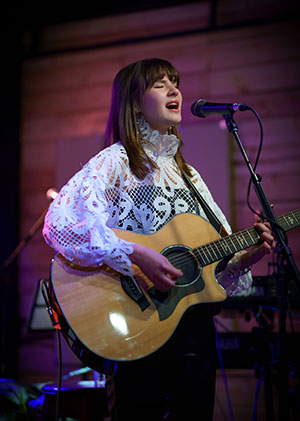 Kateryna Grace for SK Arts Arts of Celebration 2025, young girl on stage singing with a guitar.